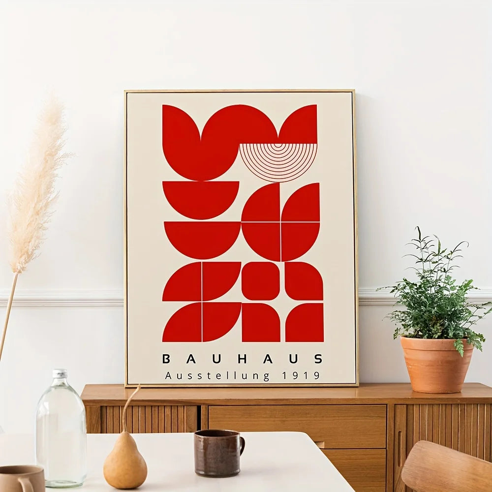 Framed Bauhaus poster with red abstract design on a wall above a wooden cabinet.