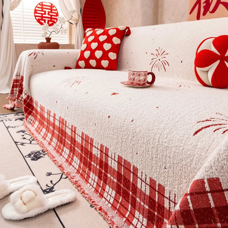 A cream-coloured quilted sofa cover featuring red fireworks and heart patterns with a checkered fringe.