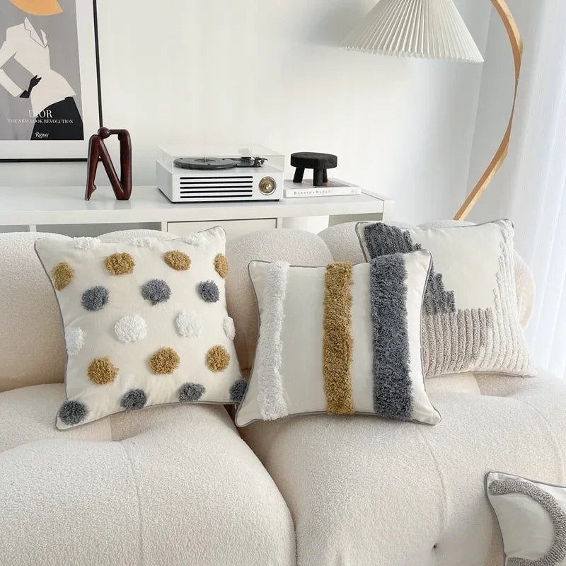 Decorative pillows on a sofa with a lamp and books in the background