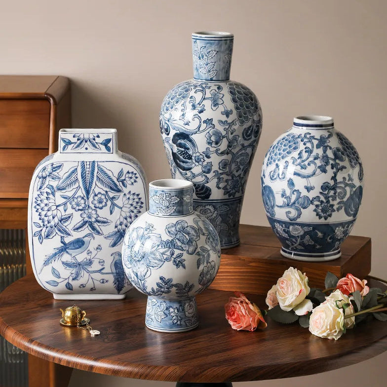 Set of blue and white patterned vases on a wooden surface with flowers and a wooden cabinet in the background.