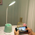 Green LED desk lamp on a marble surface with a person using a smartphone.
