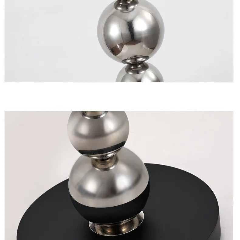 Metallic decorative lamp base with spherical design on a black base against a light grey background