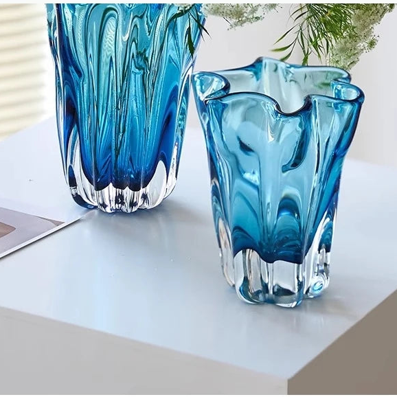 Two blue glass vases on a white surface with a blurred background