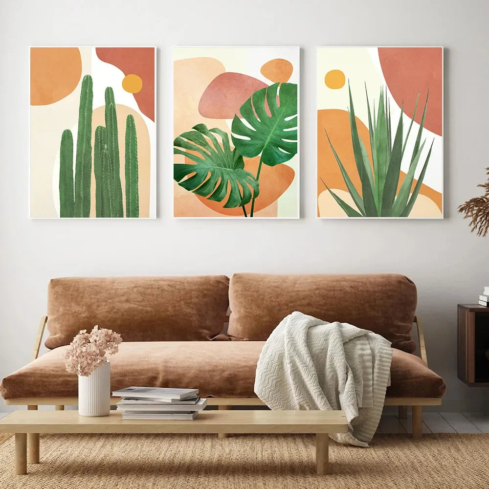 Three abstract plant-themed wall art pieces above a brown sofa in a living room.