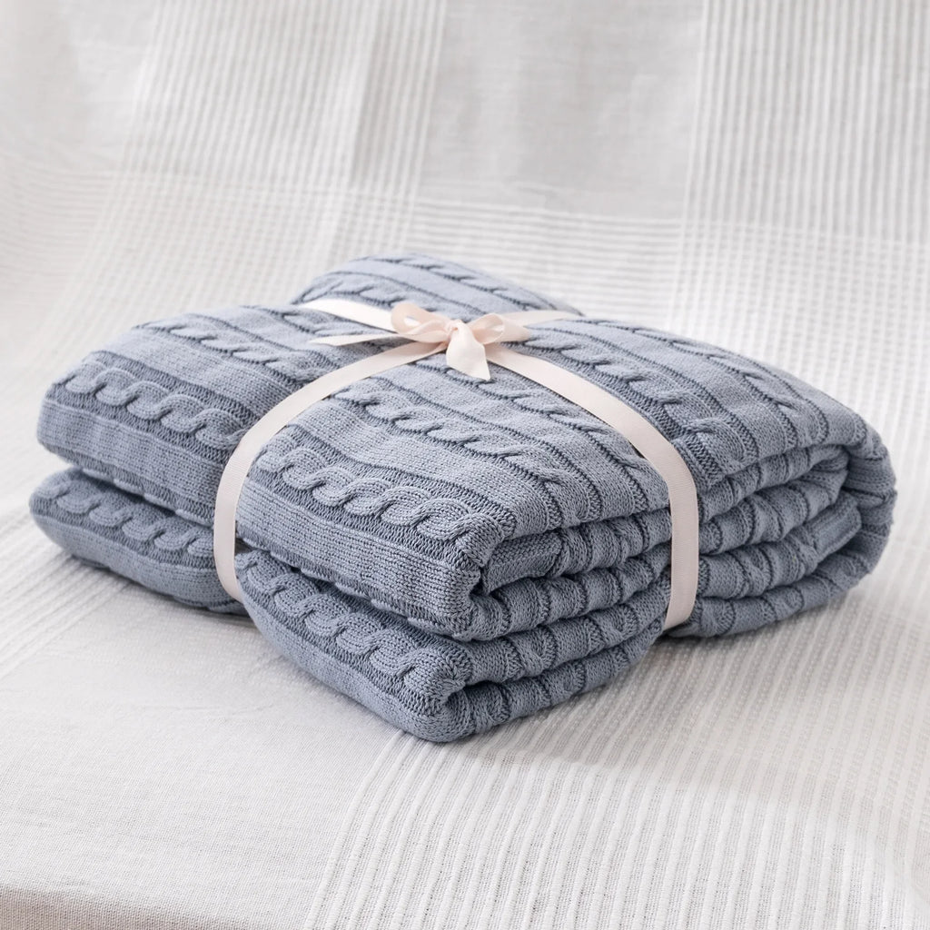 Folded blue textured blanket tied with a ribbon on a light gray background