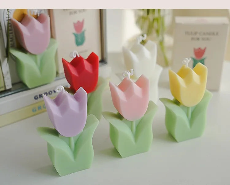 Set of tulip-shaped scented candles in various colours on a white surface.