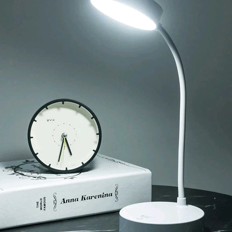 White desk lamp and round clock on a book with a gray background