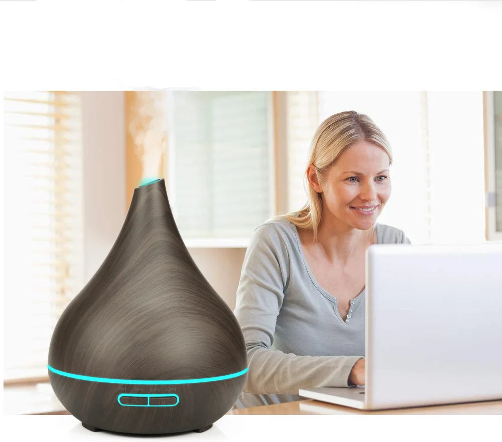 Woman using a laptop with a black essential oil diffuser on a desk