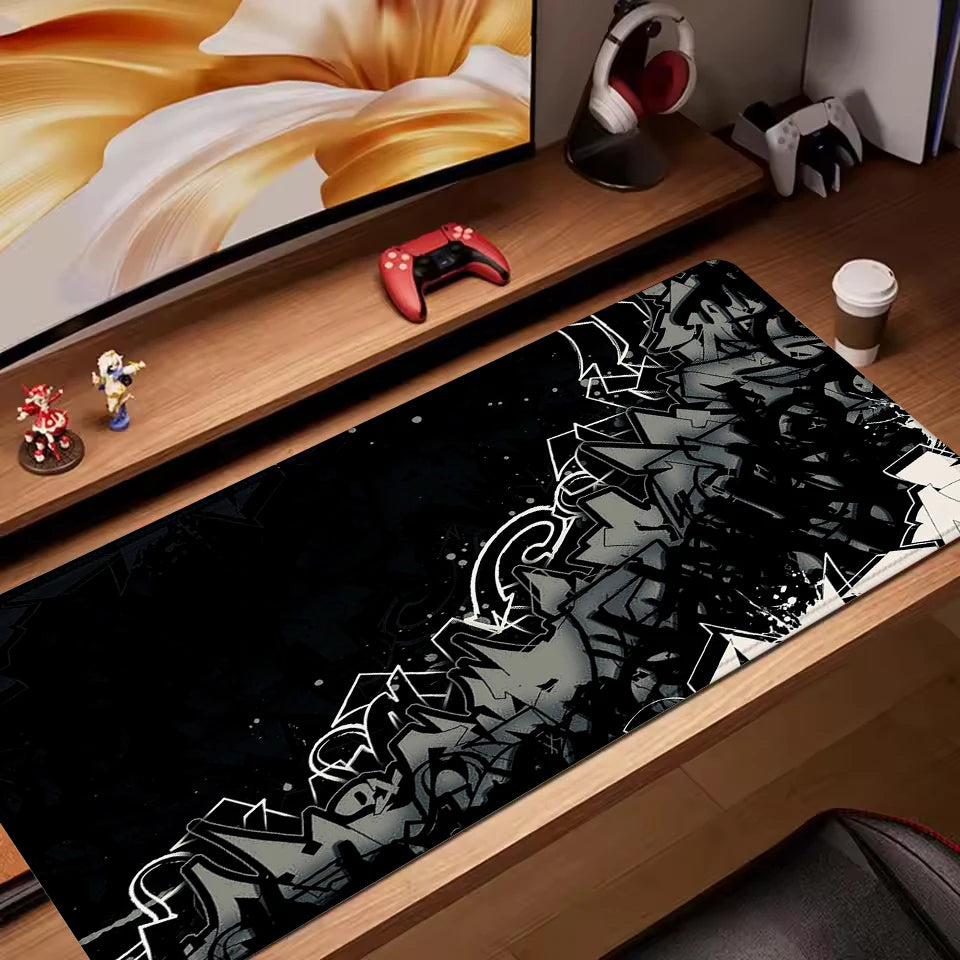 Black extended mouse pad with grey and white graffiti-style abstract design on a gaming desk