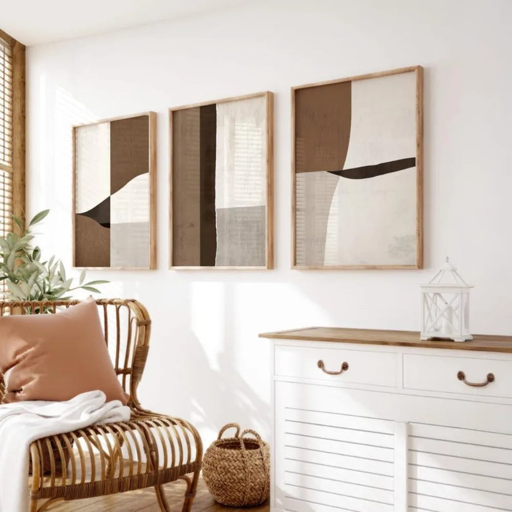 Three abstract art pieces on a wall above a white cabinet with wicker chair and basket.