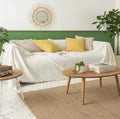 Cream coral fleece sofa cover with fringe trim styled in a bright living room