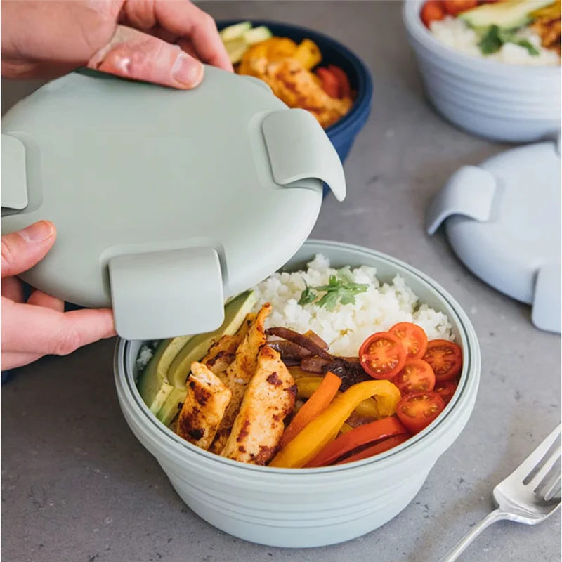 Light Green silicone lunch box opened to reveal a fresh meal of chicken, rice, and vegetables.
