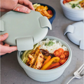 Light Green silicone lunch box opened to reveal a fresh meal of chicken, rice, and vegetables.