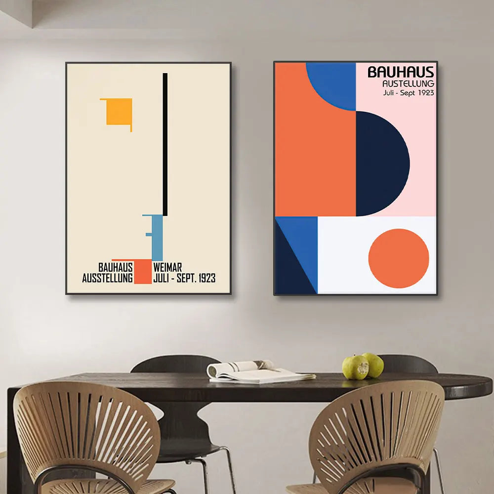 Two abstract art posters on a wall above a dining table with chairs.