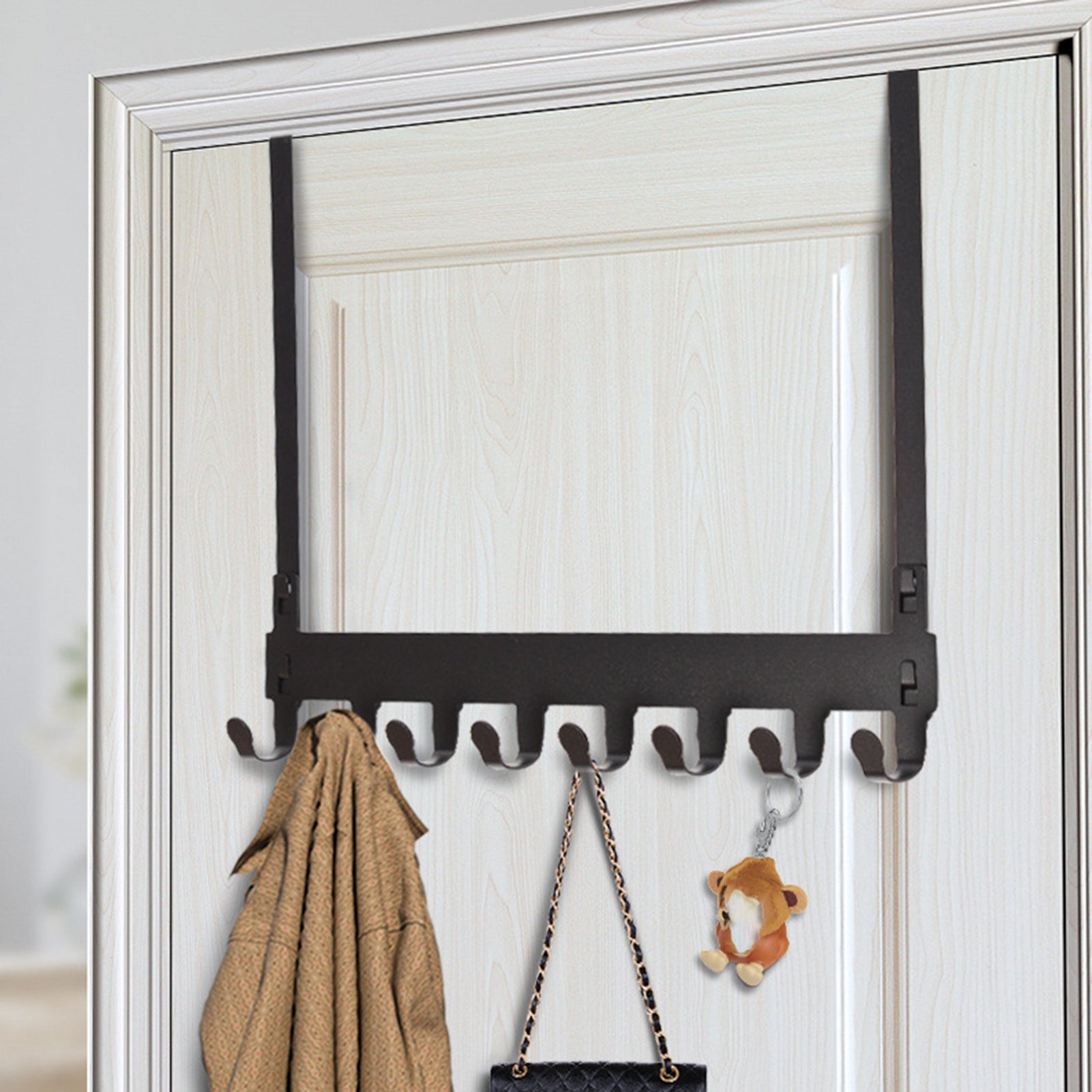 Black over-the-door organiser rack holding a coat, a handbag, and a keychain on a door