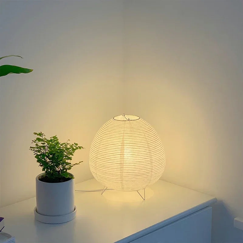 Japanese-style round lamp and potted plant on a surface with a soft light background