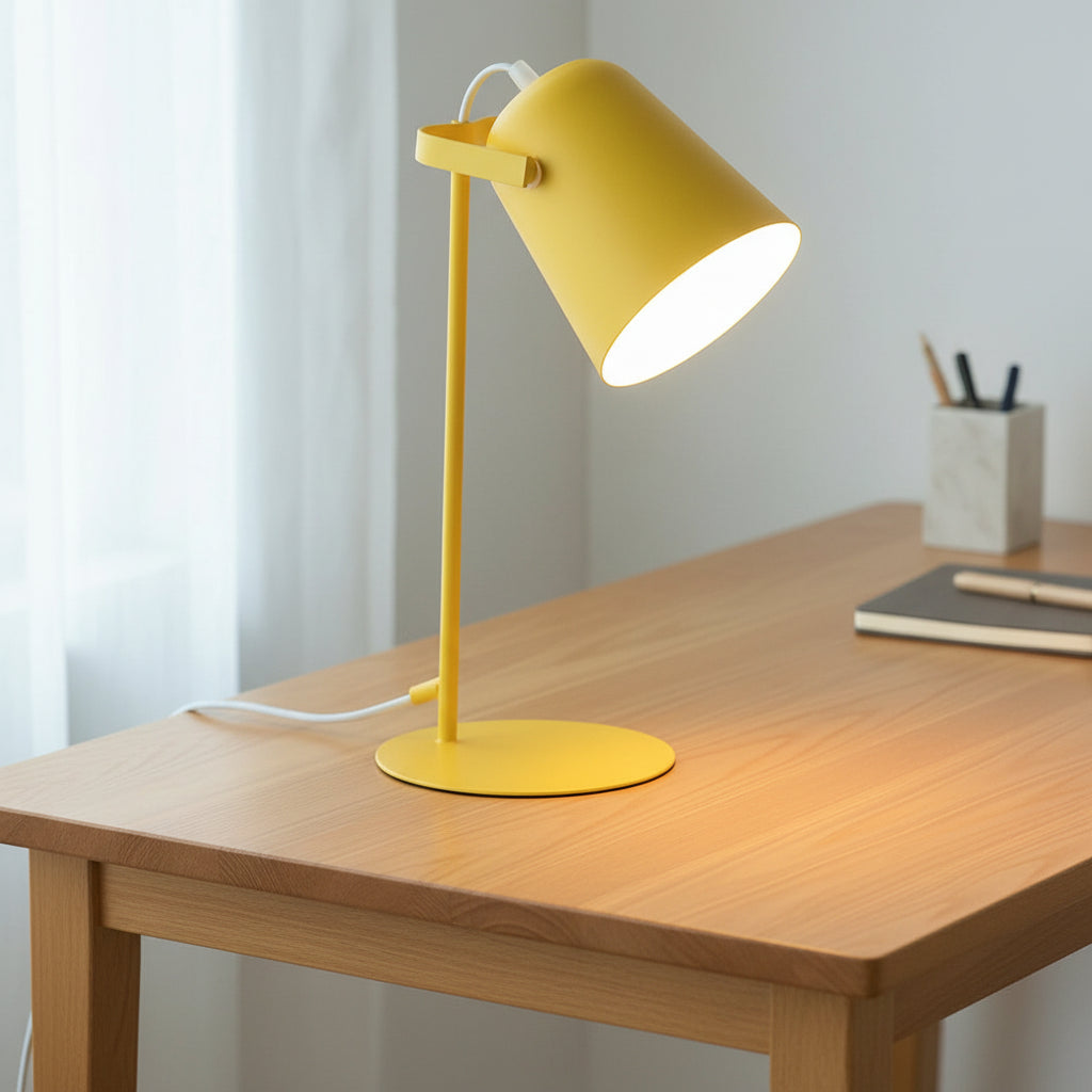 Yellow table lamp on a white surface with a vase and framed picture in the background