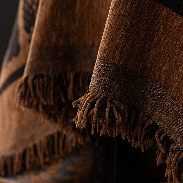 Close-up of a brown plaid blanket with fringes on a dark background