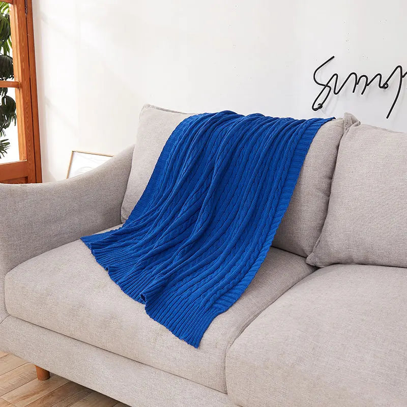 Blue blanket draped over a gray sofa in a living room setting.