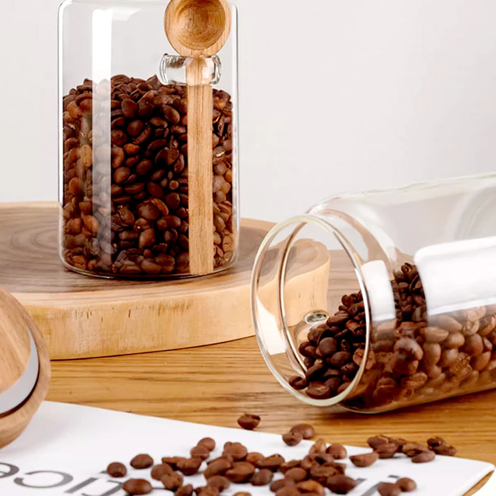 Glass jar with coffee beans and wooden scoop on a wooden surface