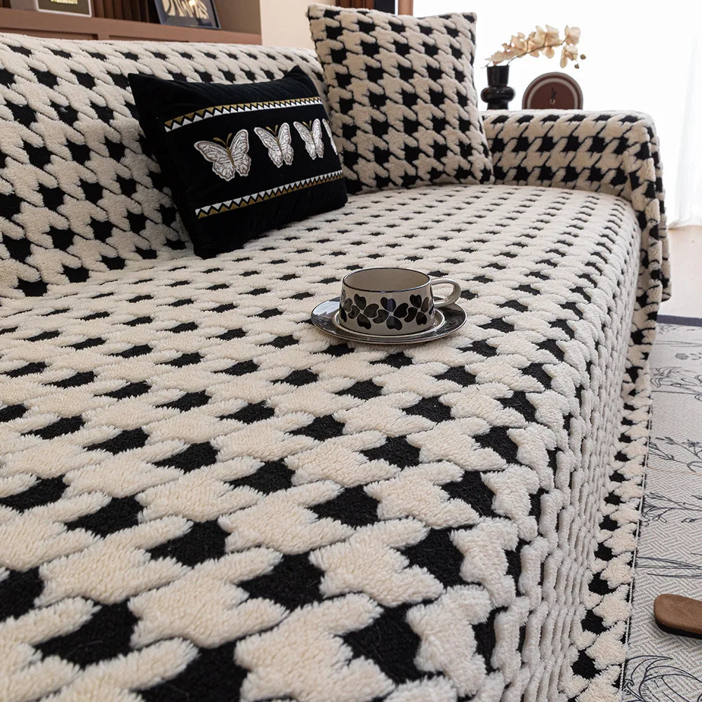 Black and white patterned sofa with decorative pillows and a cup on a small table.