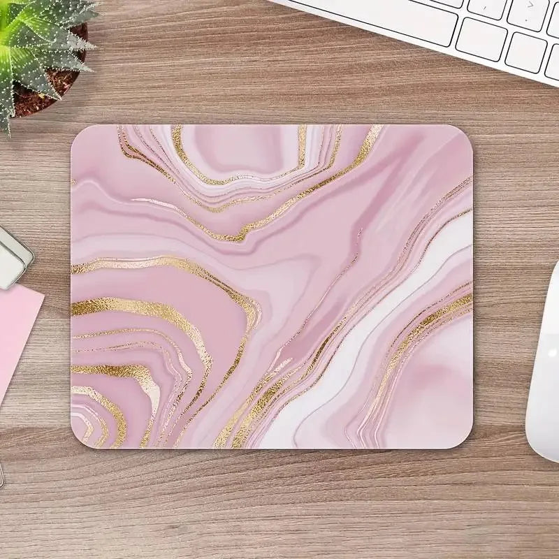Pink and gold marbled mouse pad on a wooden desk with office items.