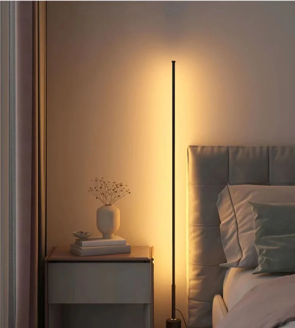 Slim black LED floor lamp casting warm ambient wall light