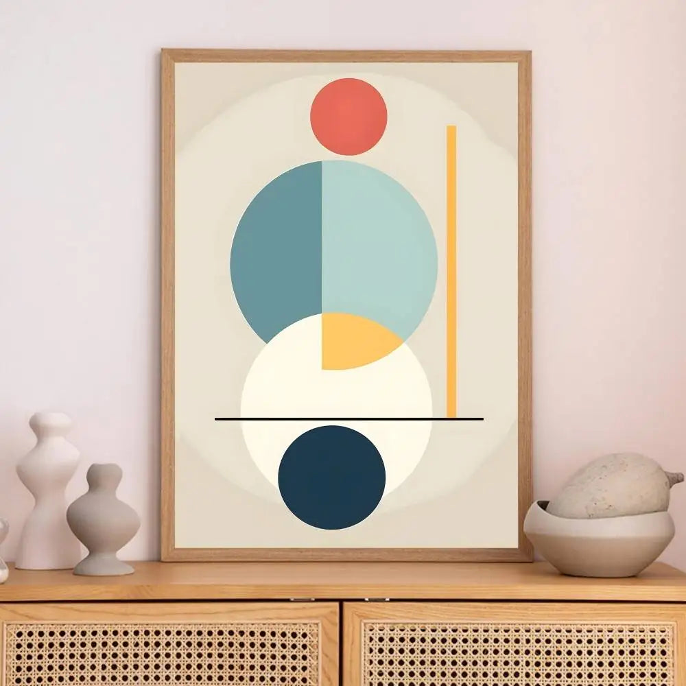 Framed abstract art with geometric shapes on a wall above a wooden cabinet.