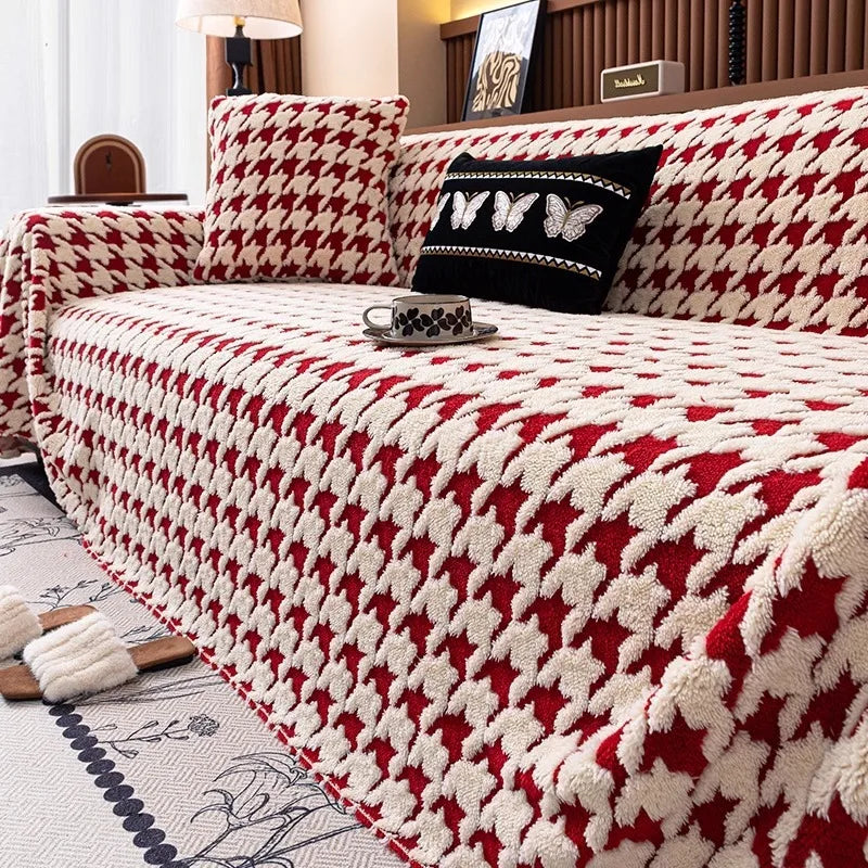 A stylish red and cream houndstooth pattern quilted furniture protector on a large sofa.