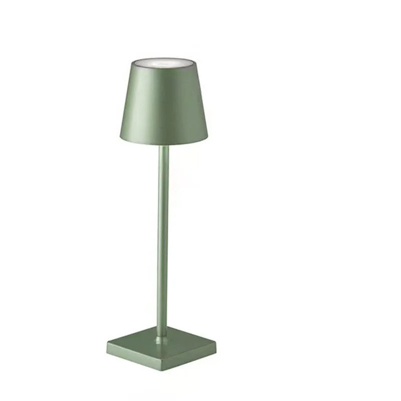 A sage green table lamp with a square base on a white background