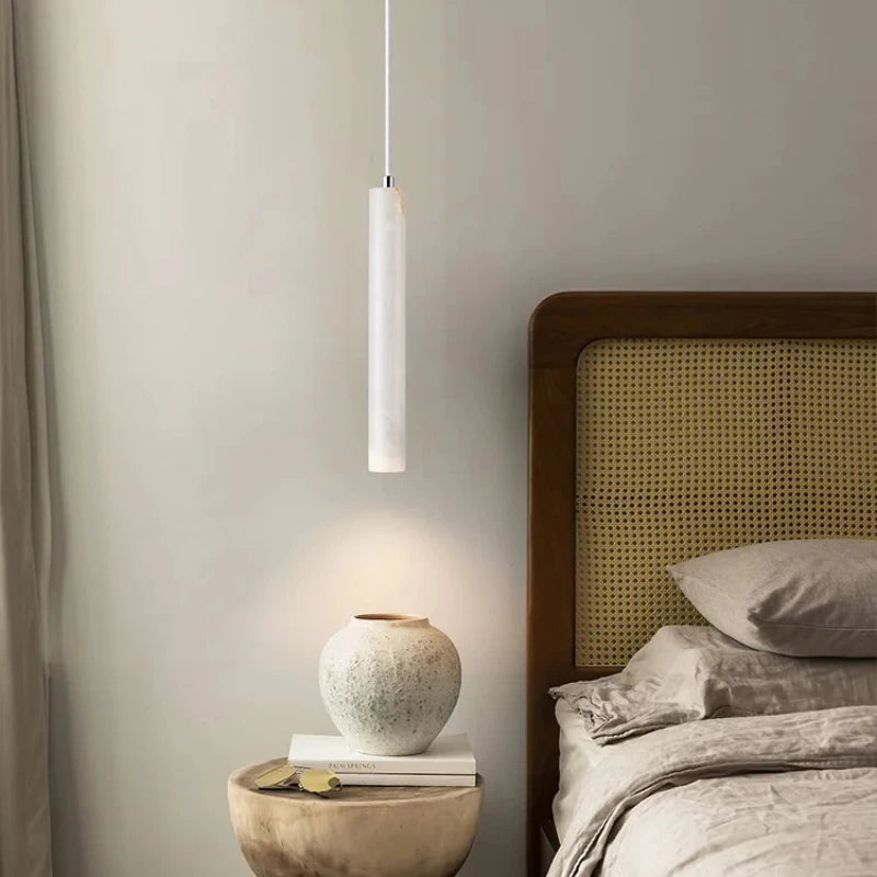 Modern bedroom with a pendant light, bedside table, and bed with wicker headboard.