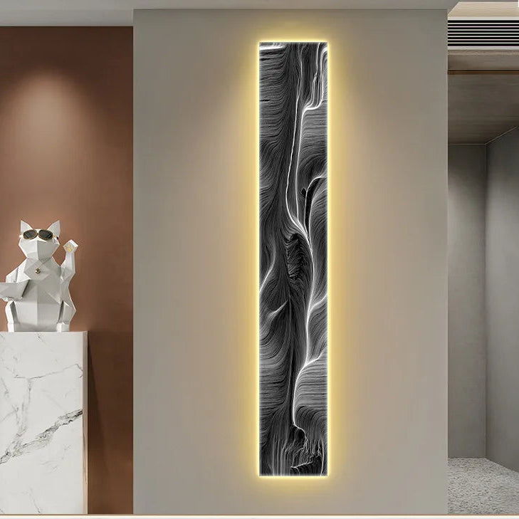 Decorative wall art with abstract design on a light grey wall, next to a white sculpture of a cat on a pedestal.