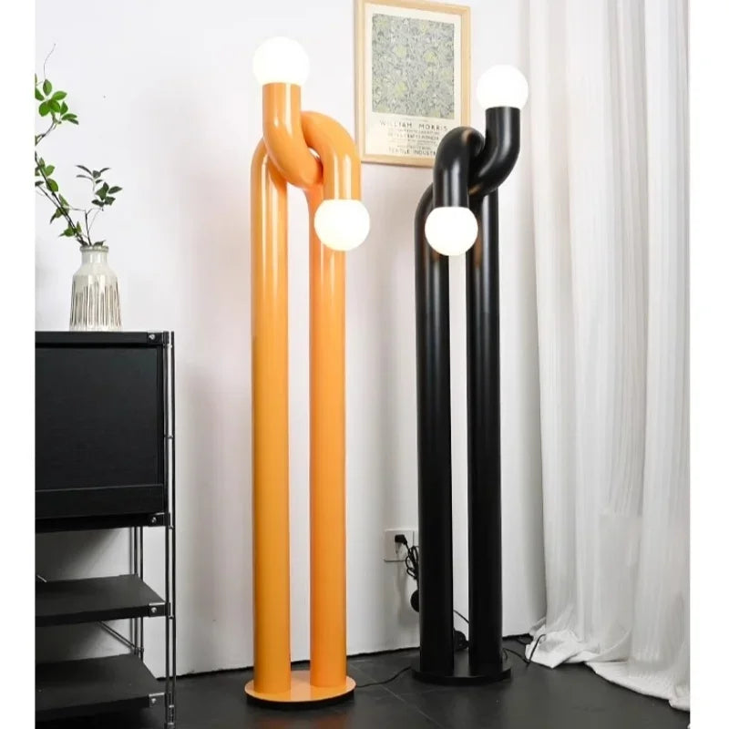 Two modern floor lamps, one orange and one black, in a room setting.