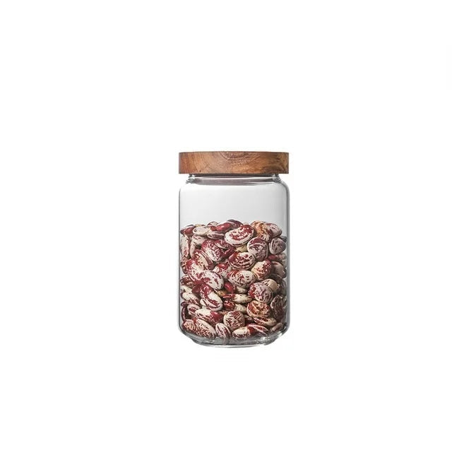 Glass jar with wooden lid containing dried fruits on a white background