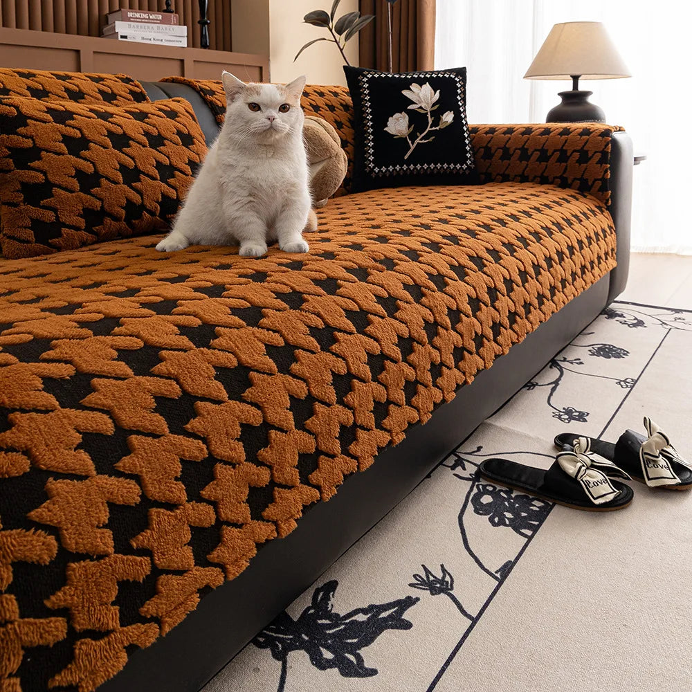 Cat sitting on a patterned orange and black sofa with a decorative pillow.