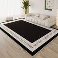 Large black area rug with cream dashed border detail in a bright minimalist living room with white cloud sofa