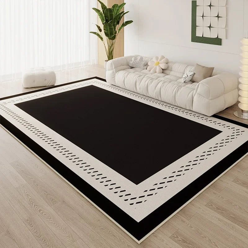 Large black area rug with cream dashed border detail in a bright minimalist living room with white cloud sofa