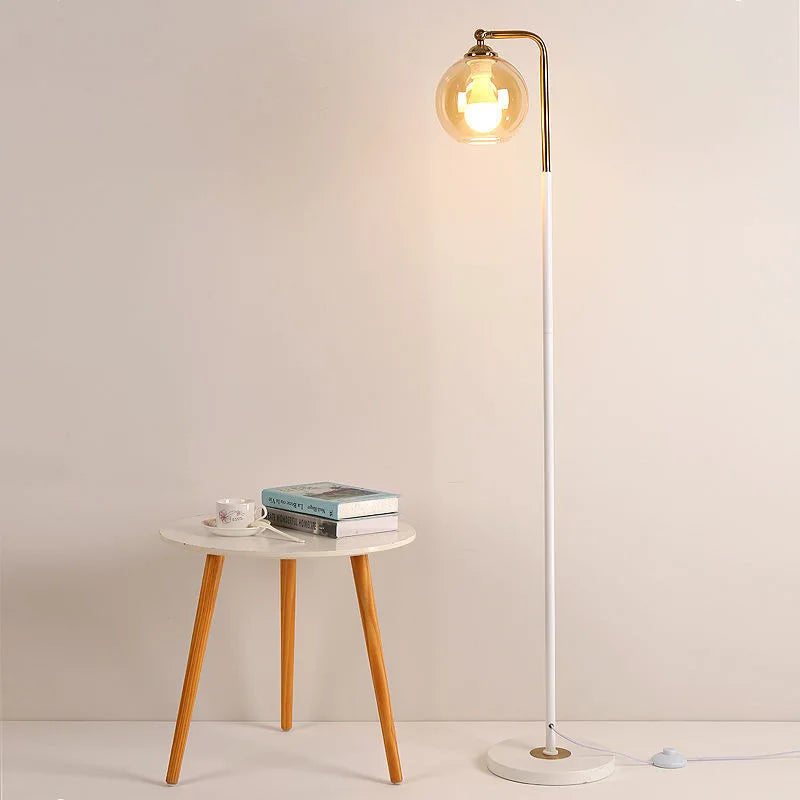 White stem brass globe floor lamp styled next to the sofa in the living room