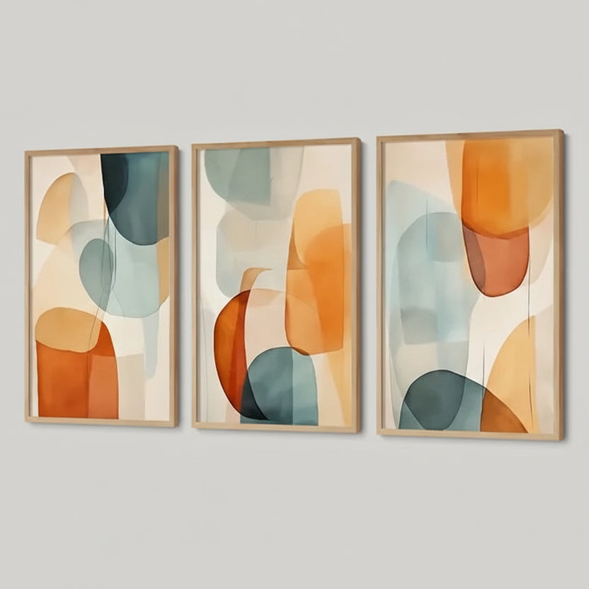 Three abstract art pieces hanging above a sofa with decorative pillows.