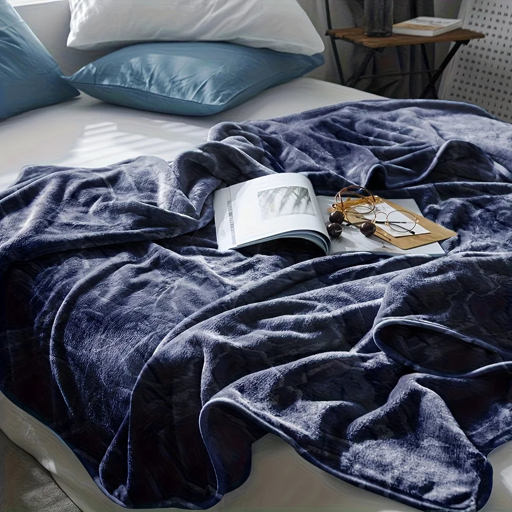 Blue blanket draped over a bed with a magazine and glasses on top