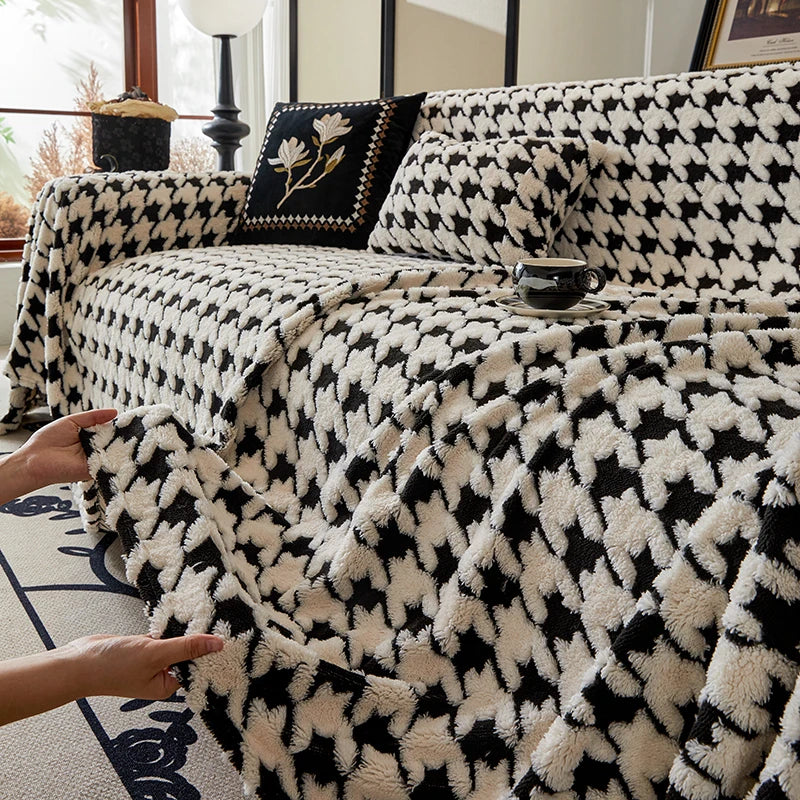Black and white patterned blanket draped over a sofa with a hand touching it.