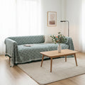 Sage green sofa cover with woven texture in a light, minimalist interior