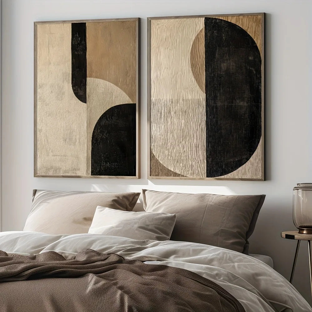 Two abstract neutral canvas prints styled above a bed with layered bedding in beige and taupe tones
