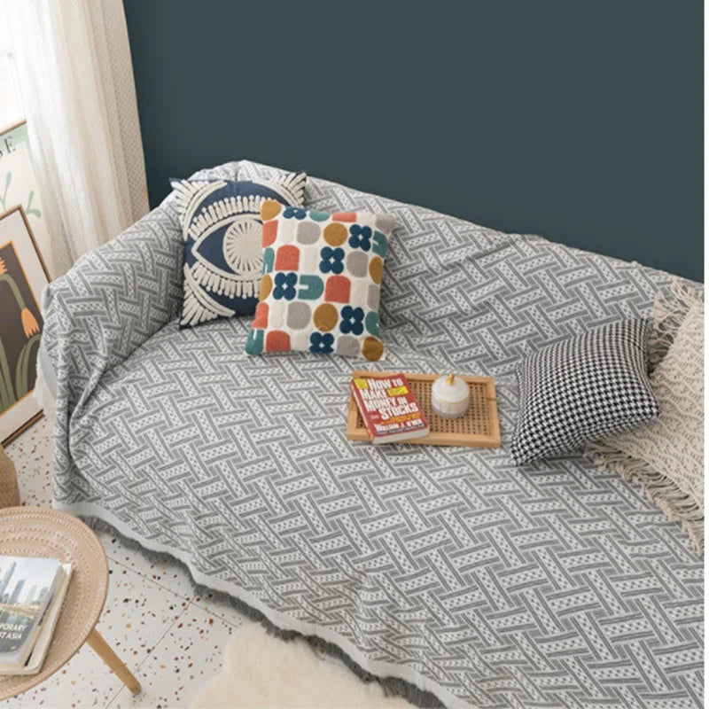 Patterned throw blanket on a sofa with cushions and a small table.