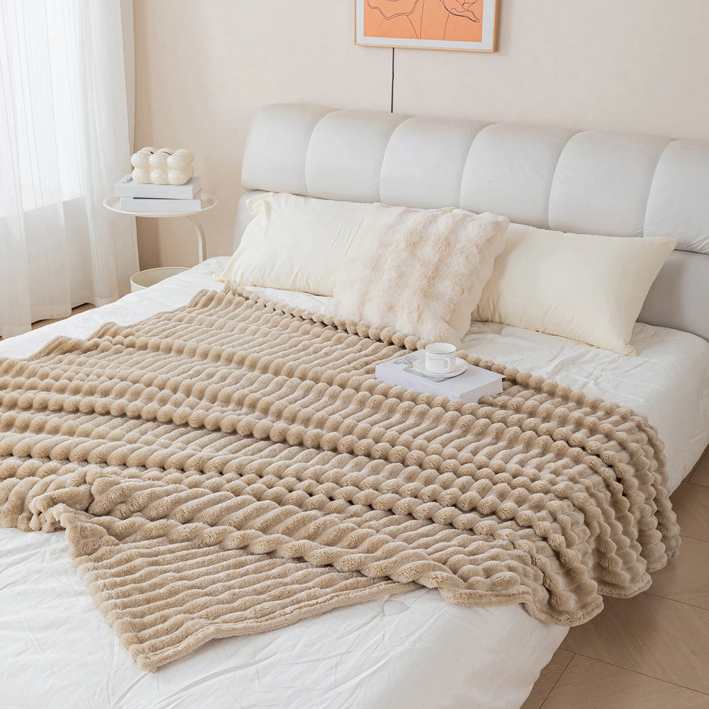 Beige blanket draped over a bed in a bedroom setting