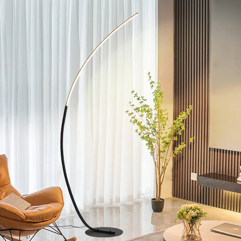 Modern floor lamp in a living room setting with a plant and chair.