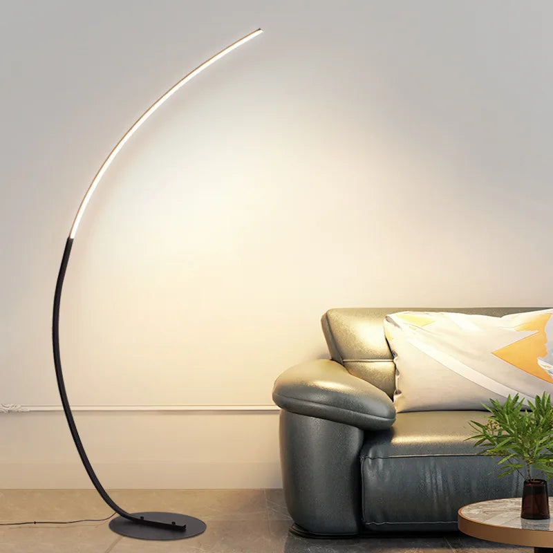 Modern floor lamp in a living room setting with a sofa and plant.