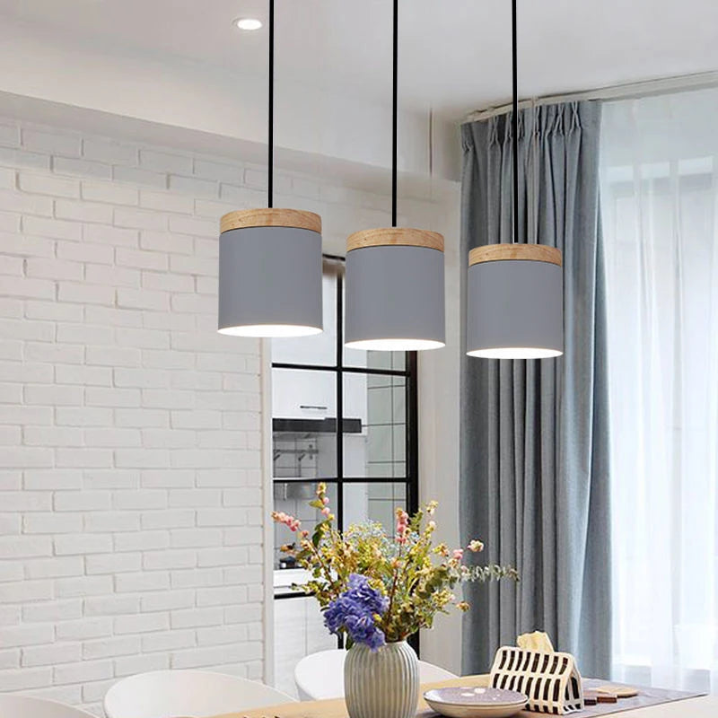 Modern pendant lights hanging above a dining table with a vase of flowers.