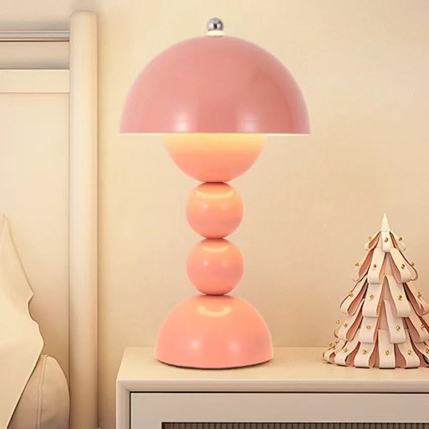Pink table lamp on a nightstand with a decorative item in the background