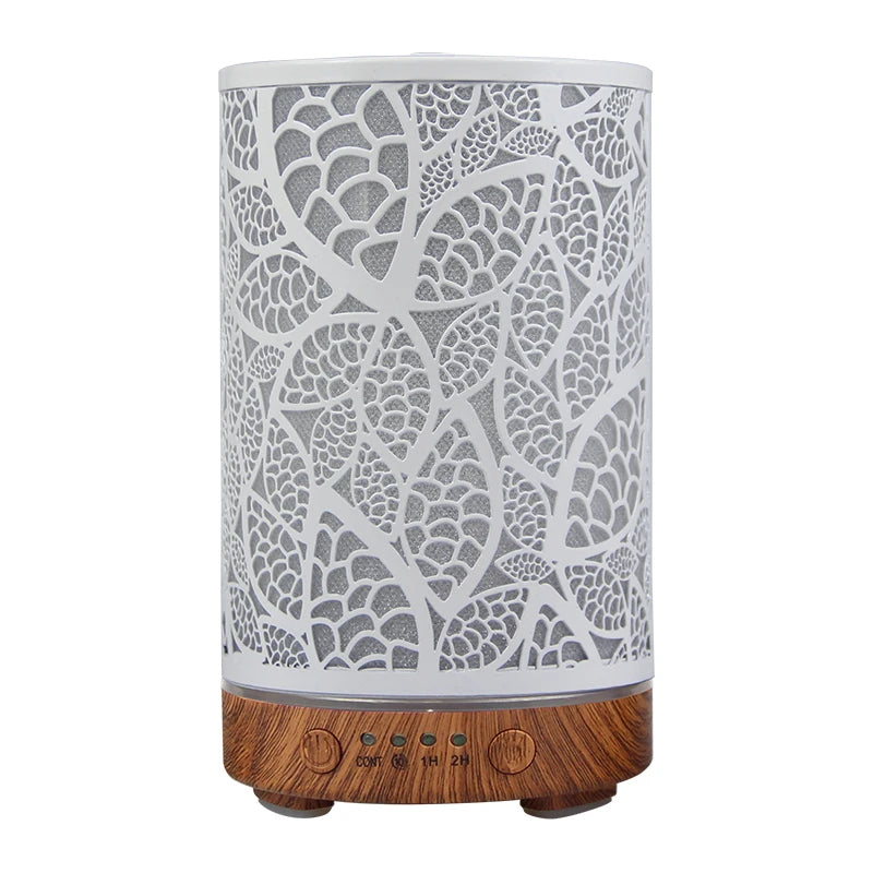 Minimalist leaf pattern essential oil diffuser with white metal sleeve and dark wood grain base.